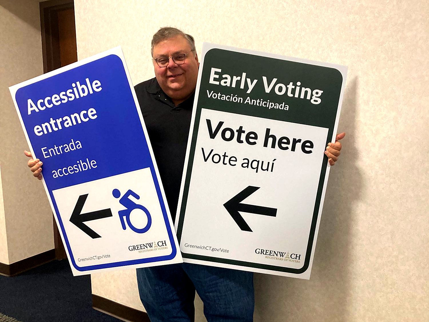 Fred DeCaro holding bilingual early voting and accessible entrance signs